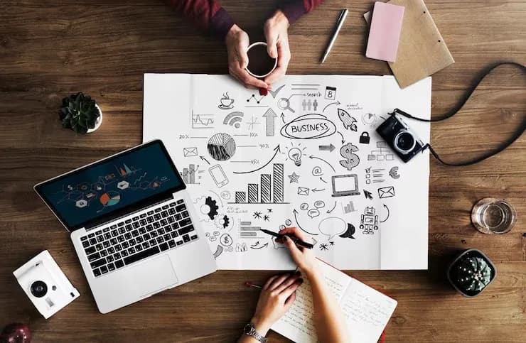 Marketing plan sketched out on paper beside a laptop showing campaign charts